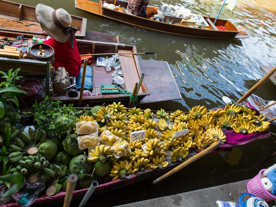 A vendor selling fruit from a boat at Damnoen Saduak floating market